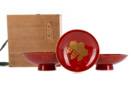 A SET OF THREE JAPANESE RED AND GILT LACQUER SAKE BOWLS