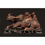 A hardwood sculpture of 2 figures on a water buffalo. China