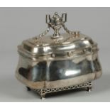 An 18th century bombarded silver tea caddy resting on trell