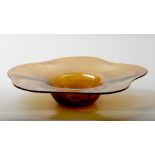 An orange mouth-blown glass dish with air bubbles, marked o