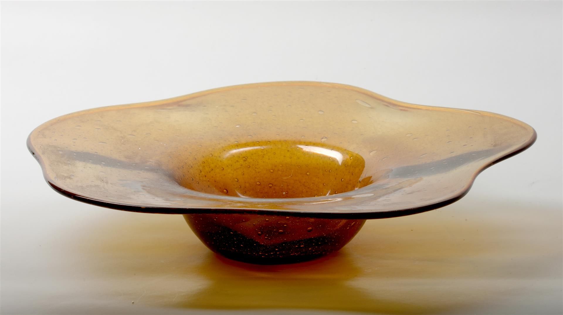 An orange mouth-blown glass dish with air bubbles, marked o