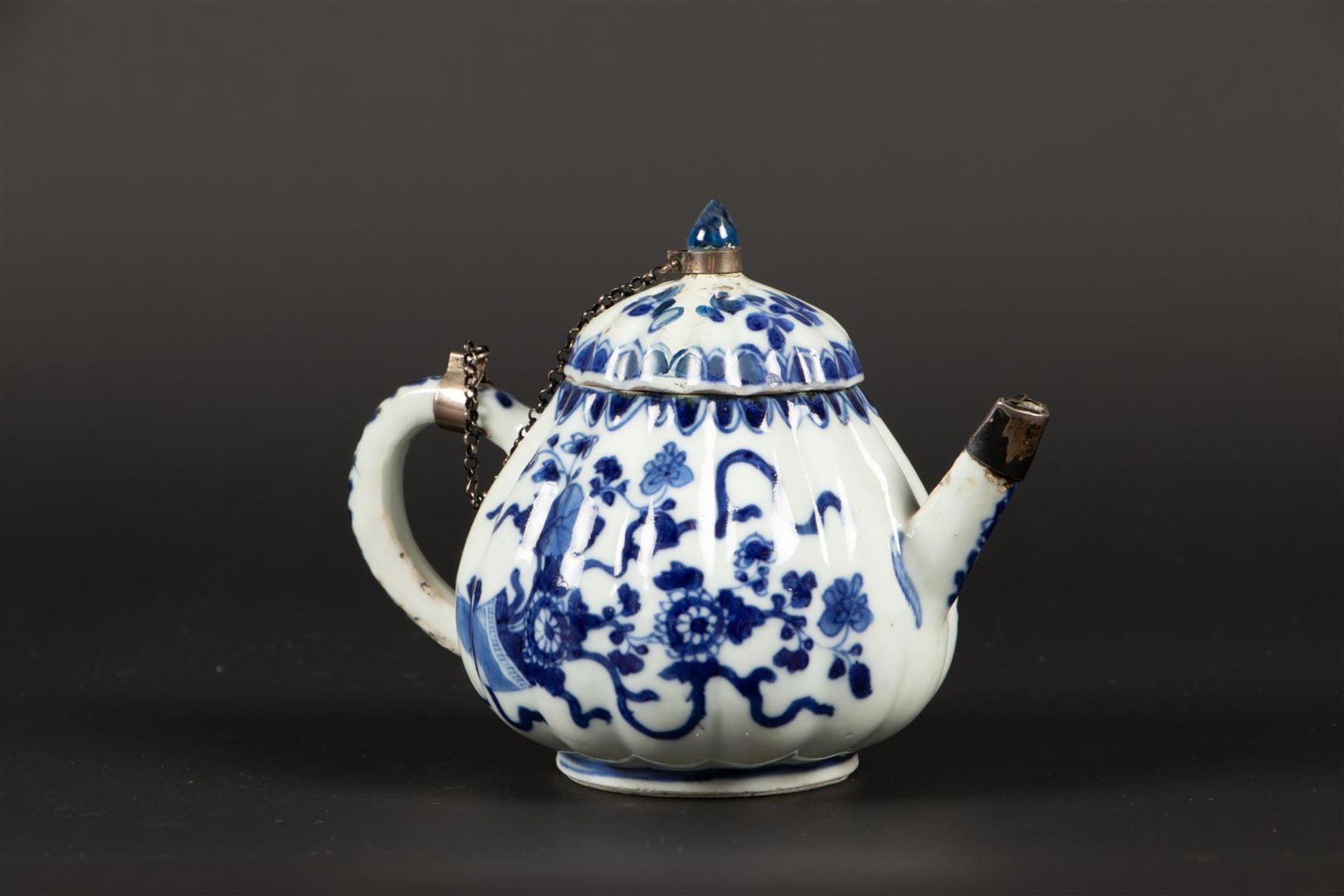 A porcelain ribbed teapot with floral decor, with silver mo