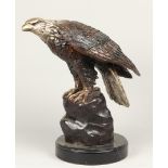 A bronze sculpture of an American eagle sitting on a rock.