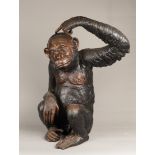 A dark patinated bronze statue of a seated chimpanzee. 2nd