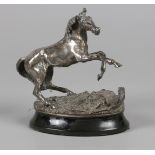 A silver sculpture of a rearing horse on a black marble bas