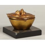 A bronze box in the shape of a bird's nest on a honed marbl