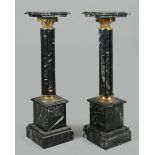 A pair of black marble columns / piedestals with bronze mou