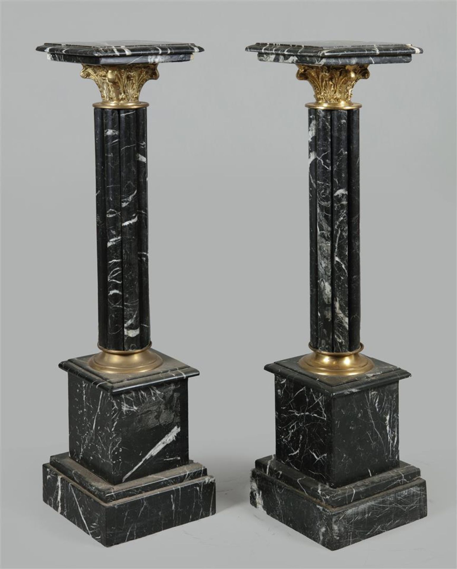 A pair of black marble columns / piedestals with bronze mou