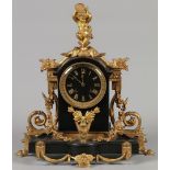 A black marble mantel clock with gilded ornaments and a fir