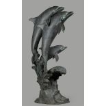 A large weathered bronze pond sculpture of leaping dolphins.