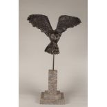 A bronze statue of a soaring owl with prey, mounted on a ma
