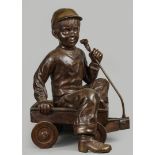 A bronze sculpture of a boy in a pull cart. 2nd half of the