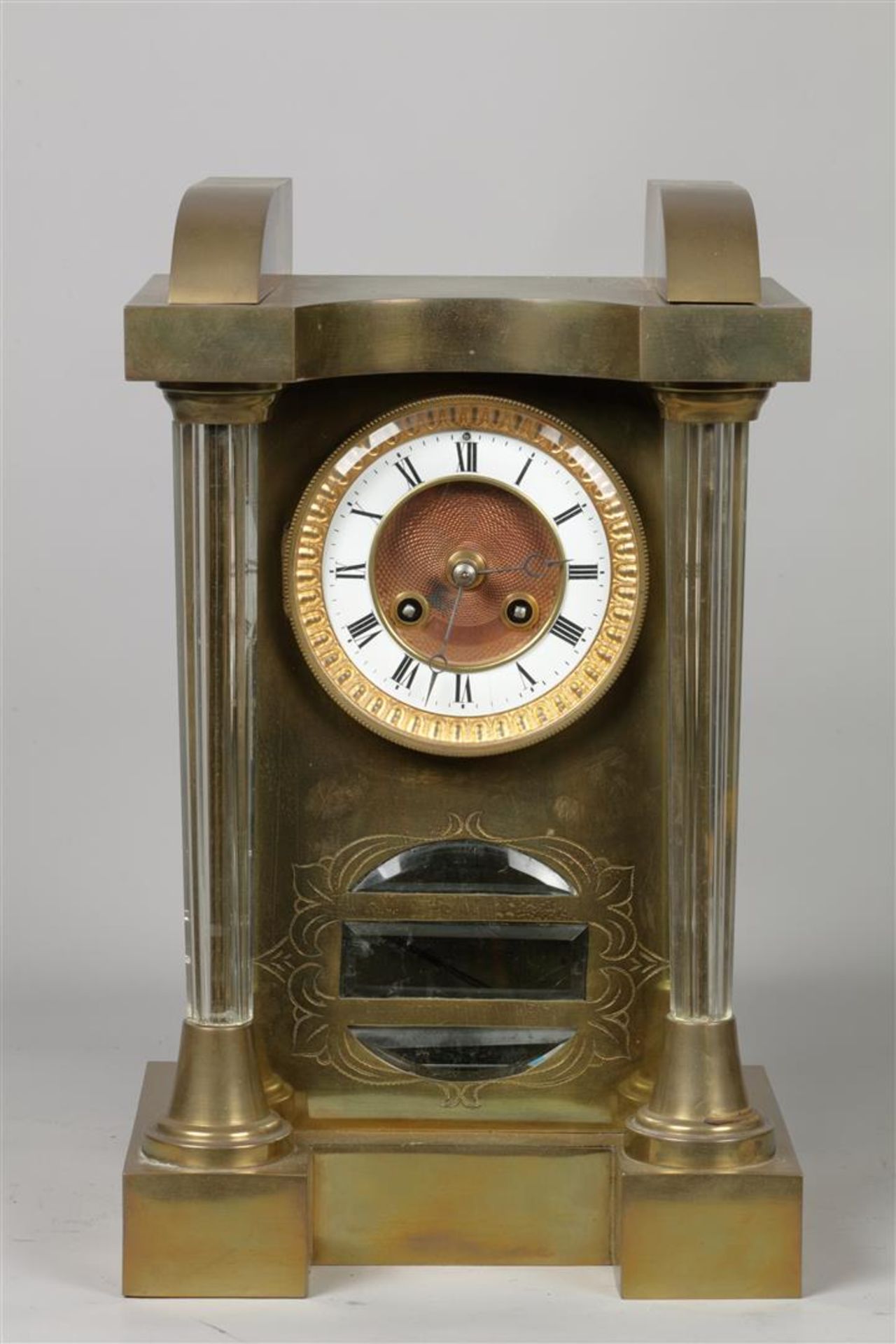 A brass mantel clock with glass columns. Early 20th century