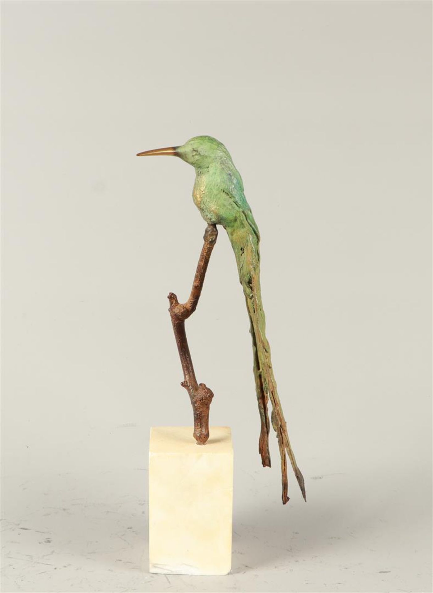 A patinated bronze of a long-tailed hummingbird sitting on 