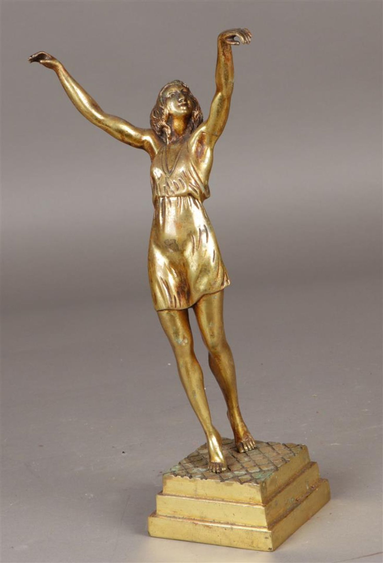 Een gepolijst bronzen beeldje van een gymnaste met geheven 
