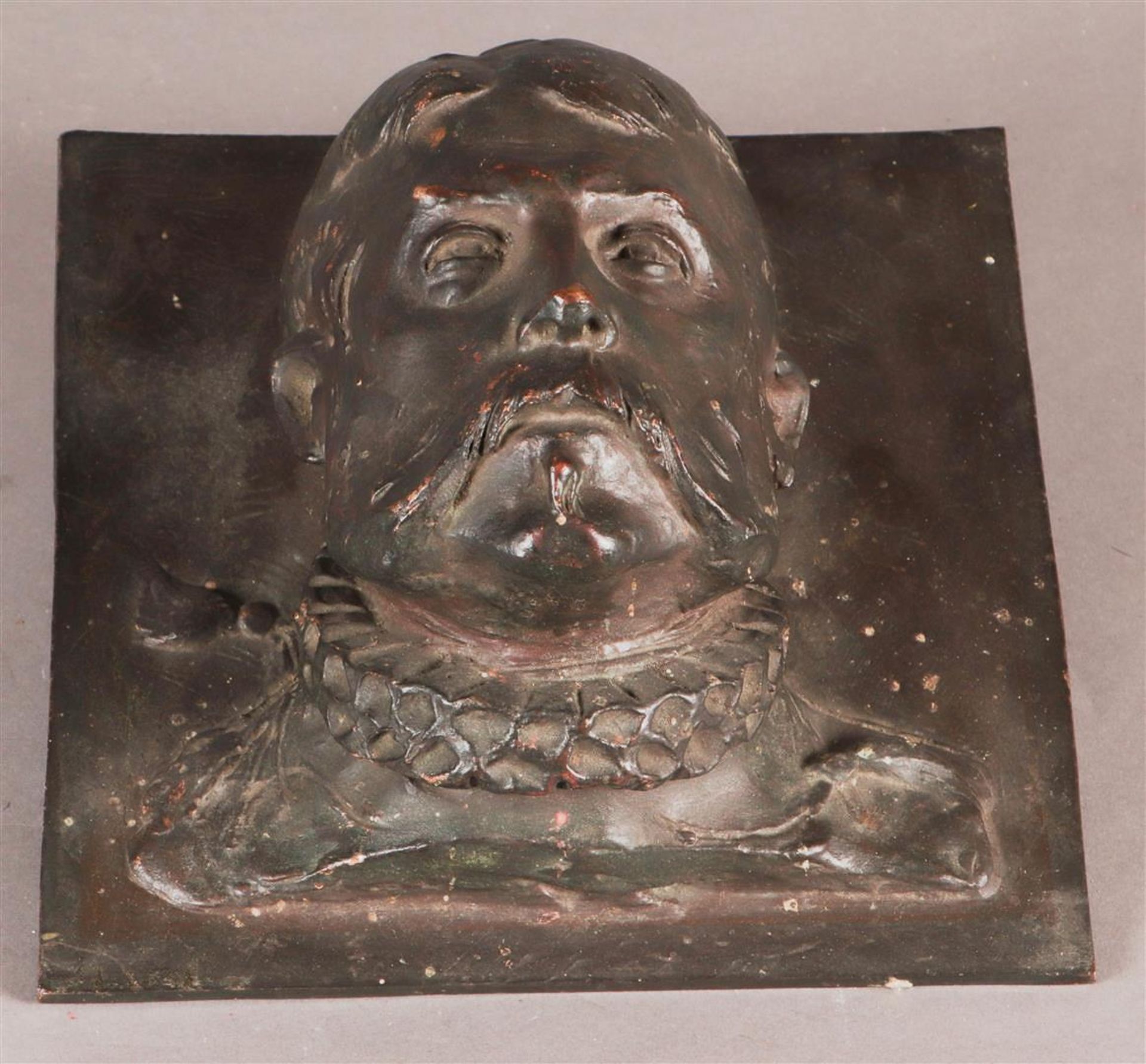 A bronze high-relief facade portrait of a man in a millstone collar.