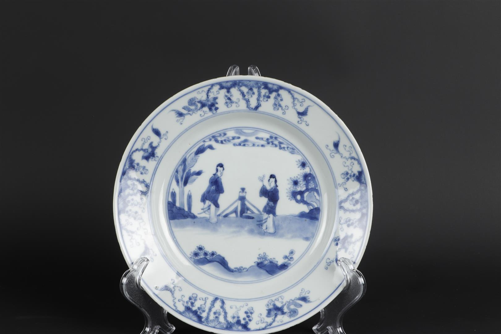 A porcelain plate with decoration in the center of two standing long lines in landscape with fence d