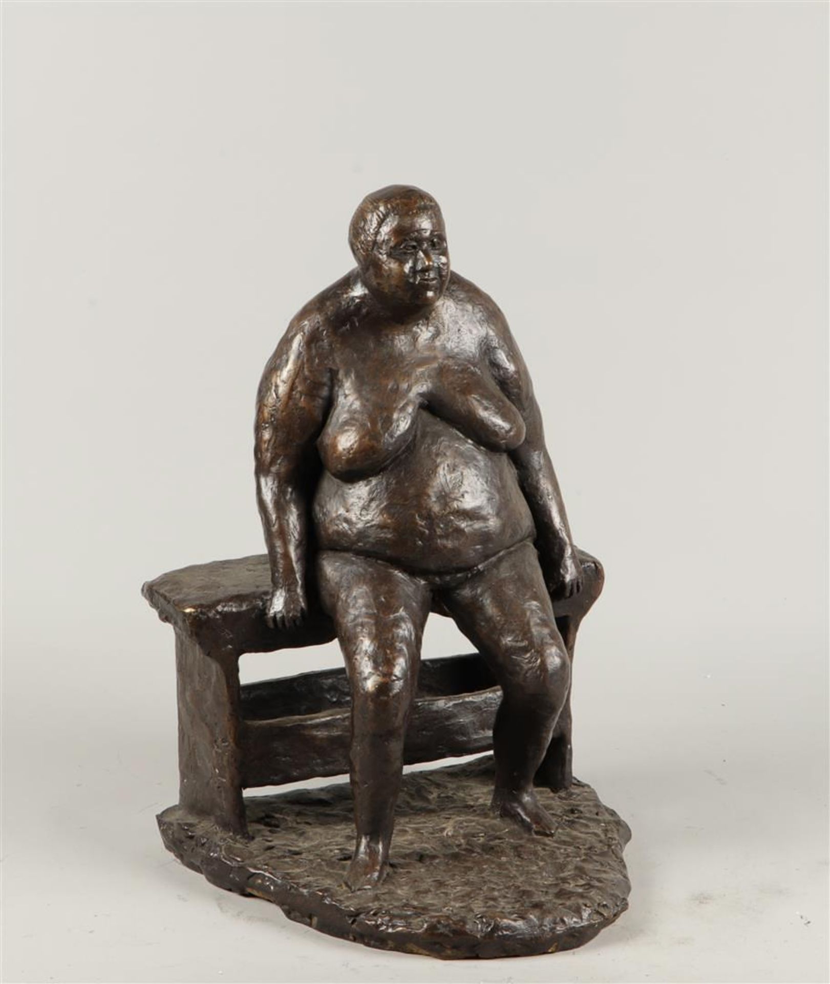 A dark patinated bronze statue of a voluptuous lady on a bench. 2nd half of the 20th century.