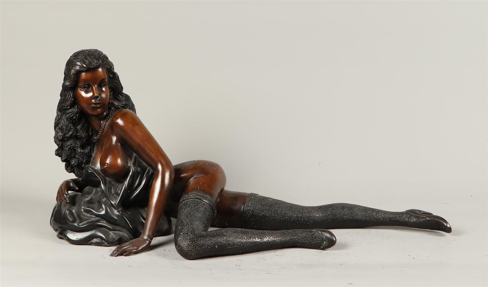 A brown and black patinated erotic bronze of a reclining lady. 2nd half of the 20th century.