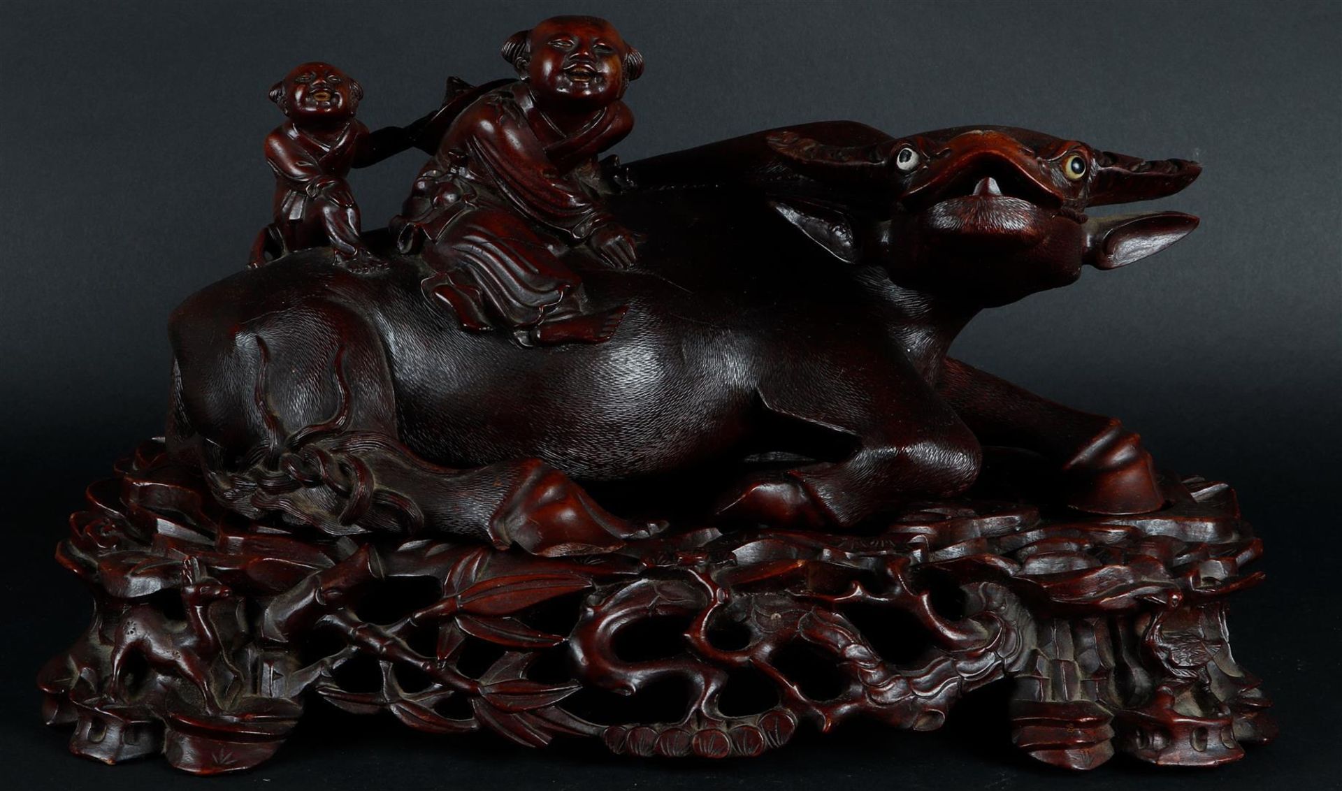 A wooden sculpture of a Chinese boy on a water buffalo, on a wooden base. China, 20th century.