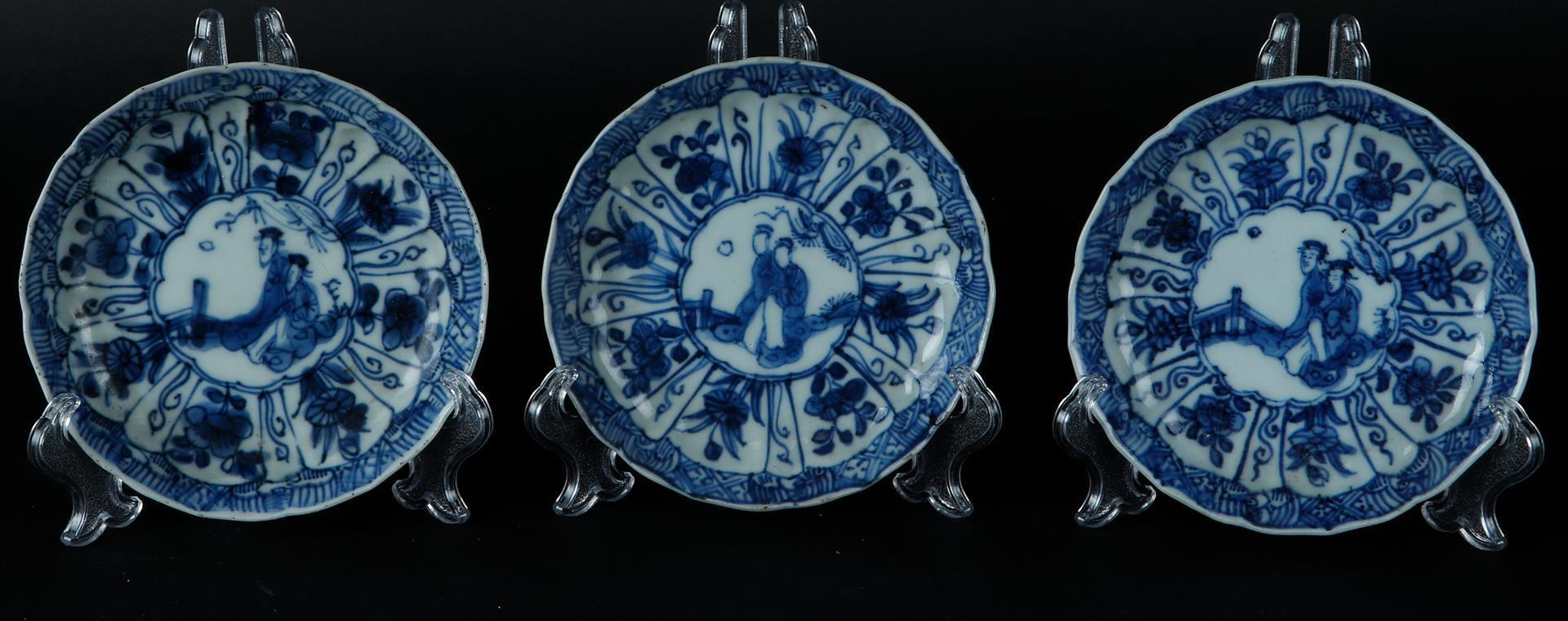 Three porcelain plates with decoration in the center of two seated figures in a landscape. China, Ka