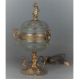A pressed glass table lamp in the shape of a coupé with a brass frame in the shape of putti and grif