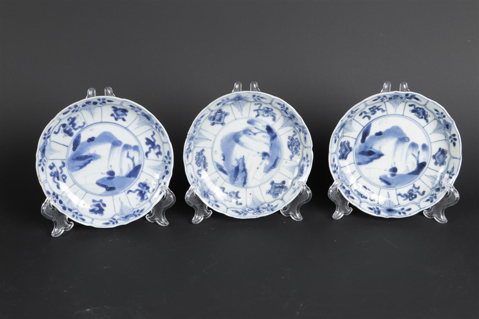 A set of three porcelain plates with landscape decor and floral decor in sections. China, Kangxi.