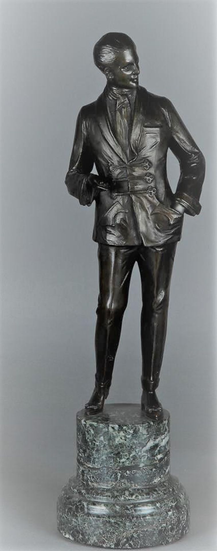 A bronze sculpture depicting a gentleman in evening jacket mounted on a green marble base. 20th cent