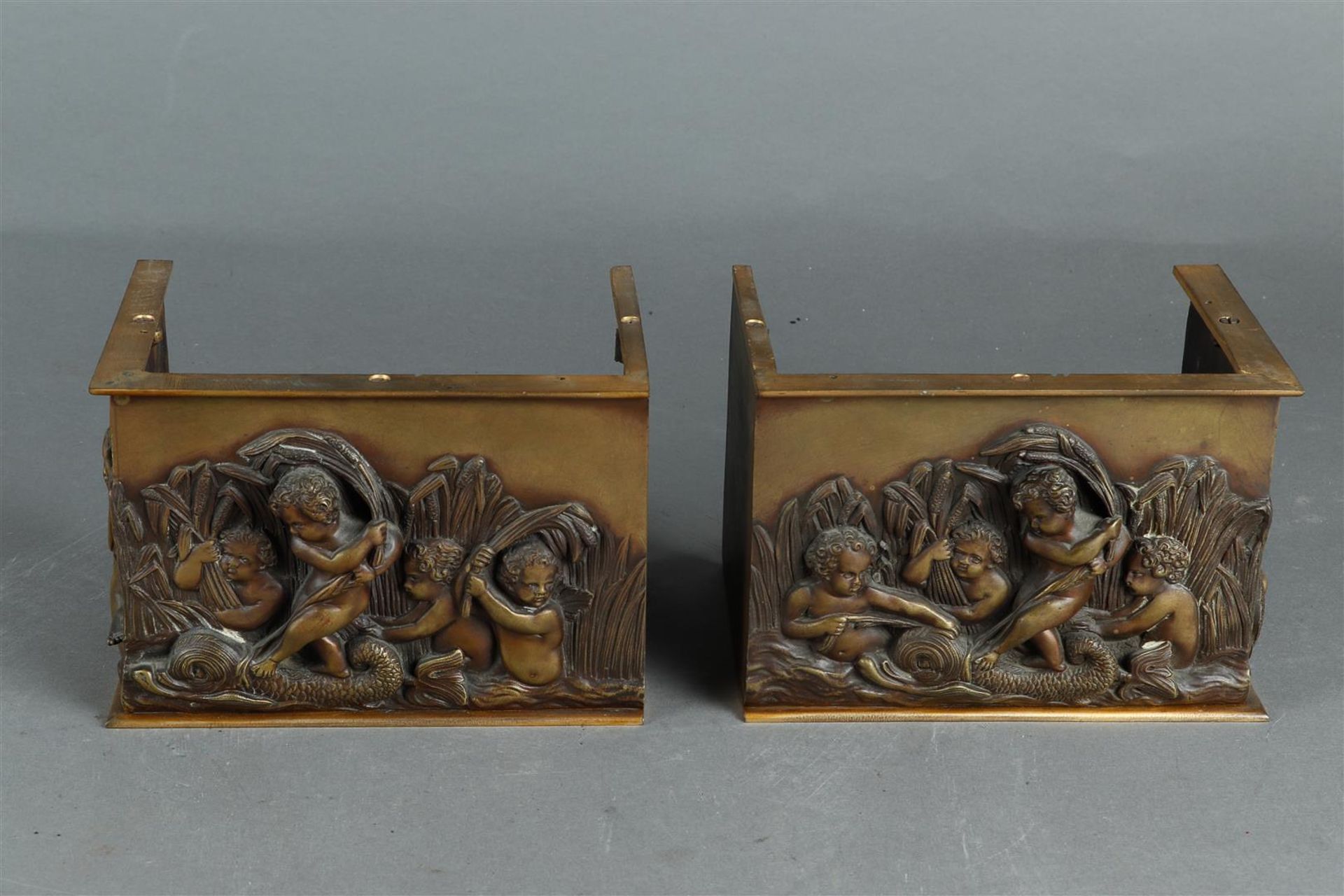 A set of cast brass fireplace ornaments with putti in a river.