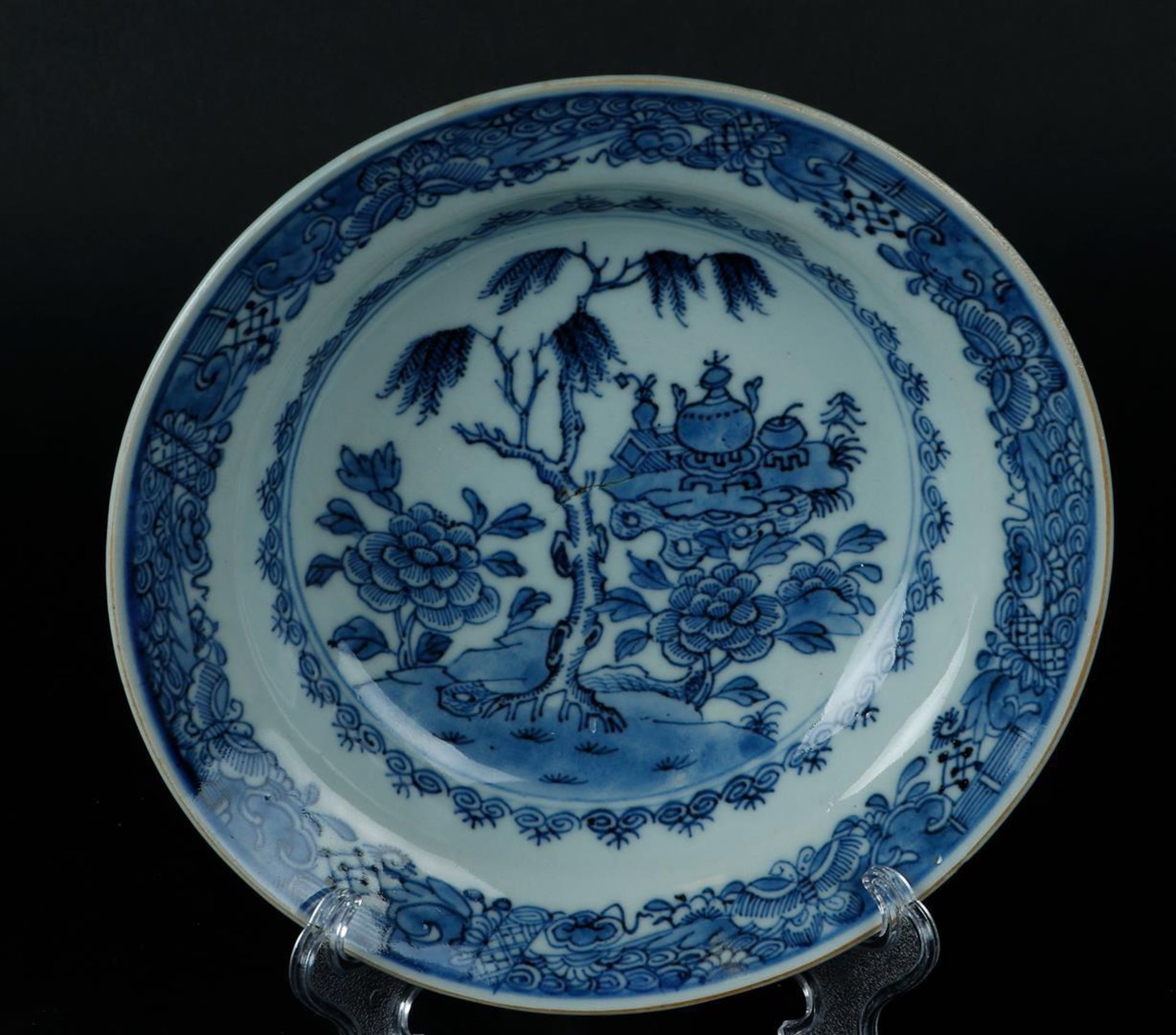 A porcelain deep plate with weeping willow and antiques on a tree stump. China, Qianlong.