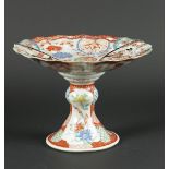 A porcelain Kutani presentation dish on a high foot with flower beds decor with figures on the outsi