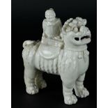 A porcelain blanc de chine foo dog with a figure on it. China, Kangxi.