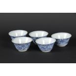 Five porcelain bowls with floral decor on the outside and a single flower in a double circle in the