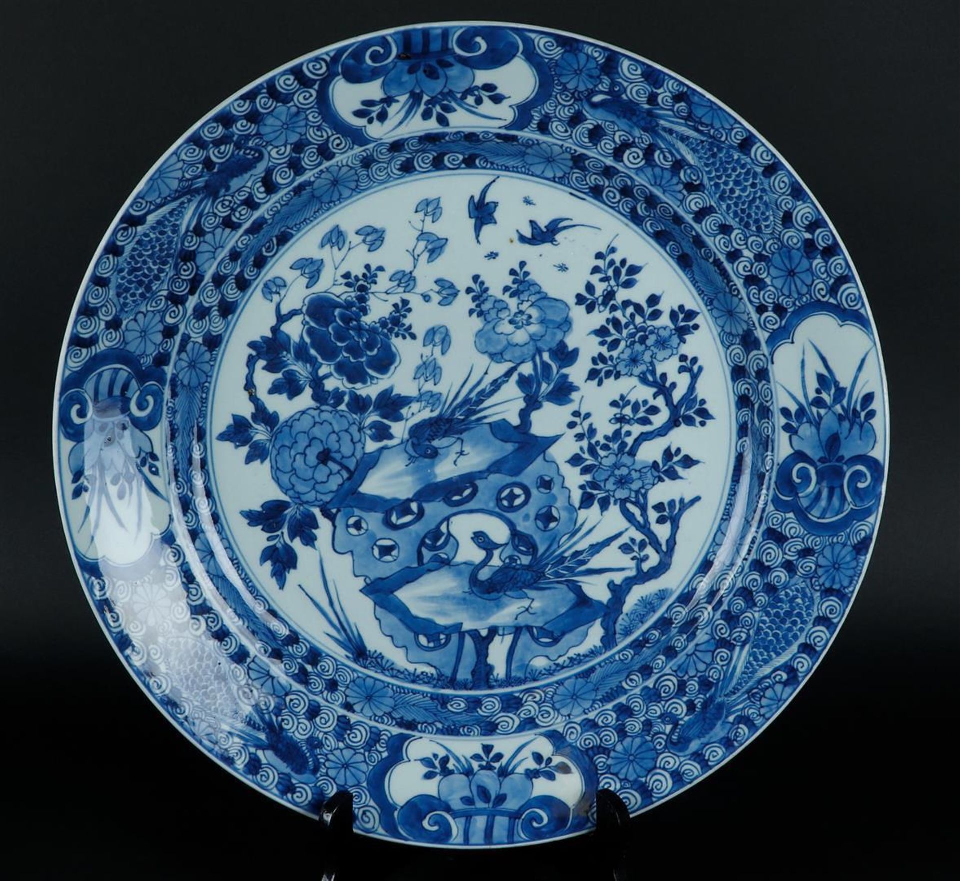 A porcelain dish with peacocks in the outer rim and with two birds of paradise on a rock decor. Chin