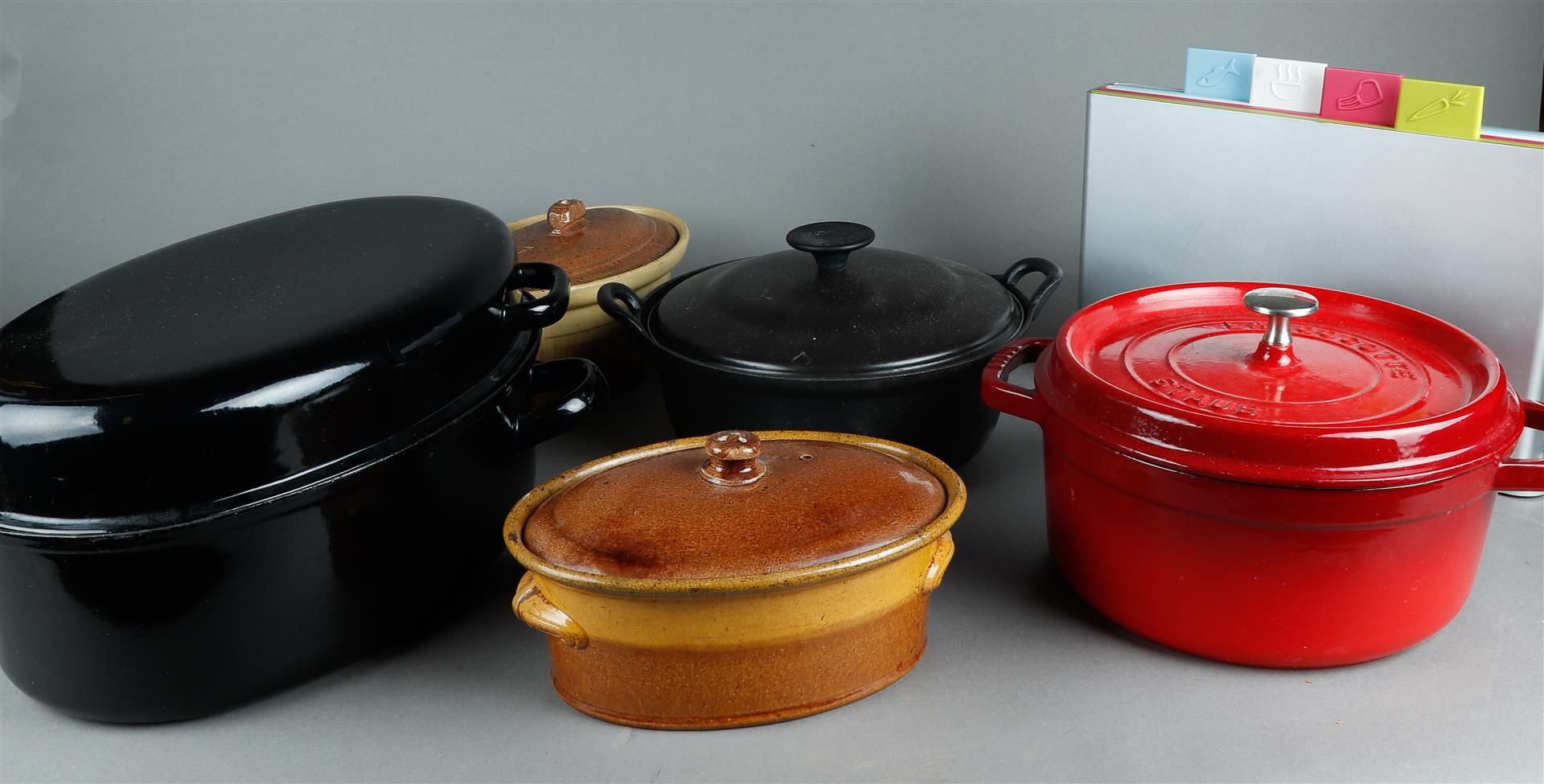 An Acotte Staub cast iron red enamel casserole. In addition, a Joseph Joseph cutting board set. In a