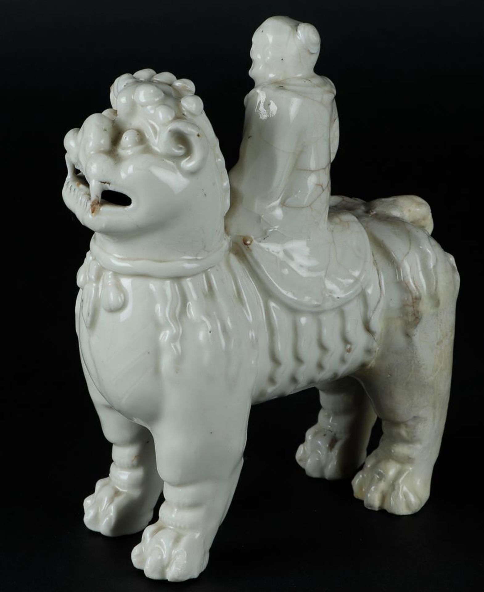 A porcelain blanc de chine foo dog with a figure on it. China, Kangxi. - Image 3 of 6
