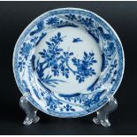 A porcelain plate with sloping outer beds with floral decor and roosters, the center with a prunus t