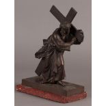 A bronze sculpture of Christ carrying the cross. Mounted on a red marble base.