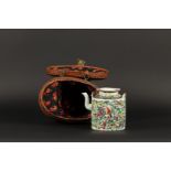 A porcelain canton teapot in matching wicker basket. China, ca. 1920.