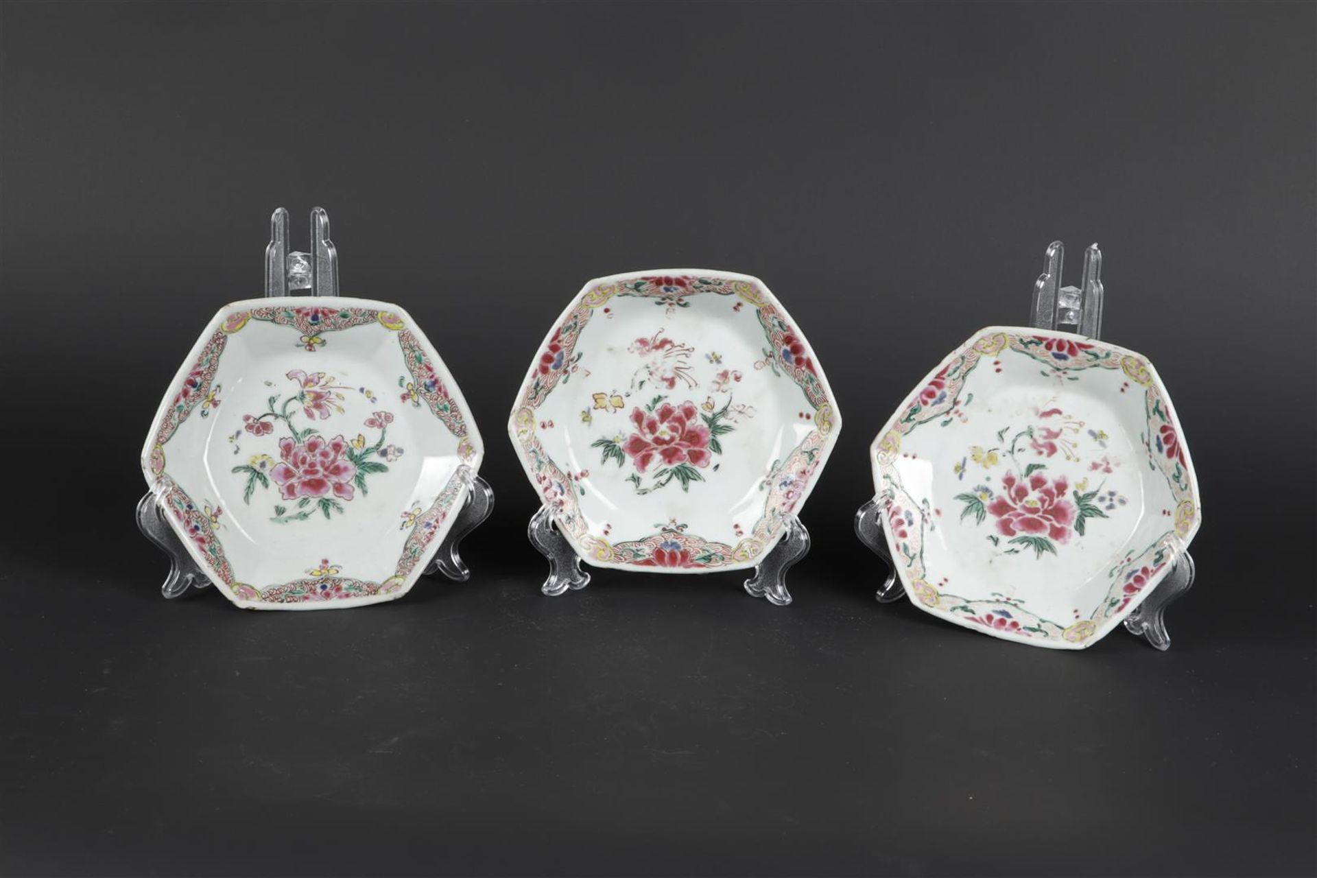 Three porcelain angled Famille Rose plates with rich floral decoration. China, Yongzheng/Qianlong.