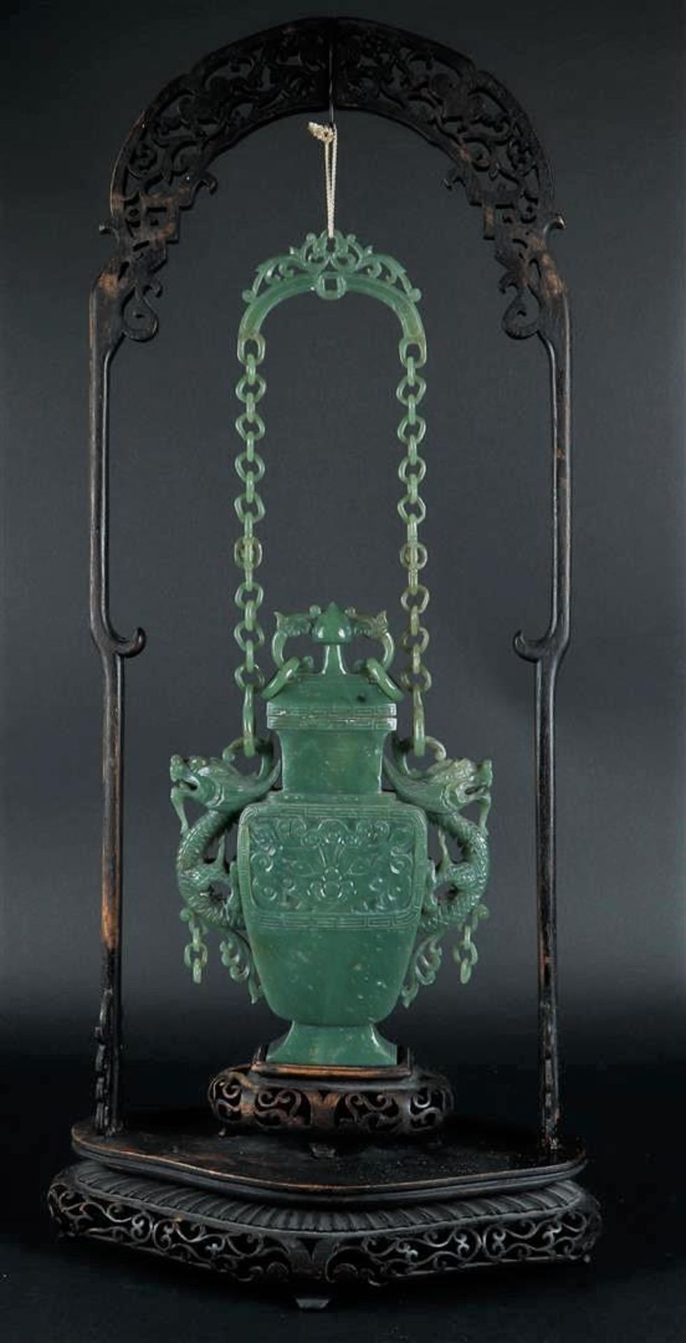 A celadon green jade vase with lid, with dragon handles and with jade chain with handle. China, 20th