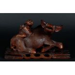 A wooden sculpture of a Chinese boy on a water buffalo, on a wooden base. China, 20th century.