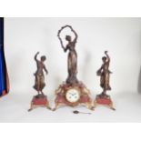A three piece Clock Garniture with bronzed female figures, the red marble clock with circular dial