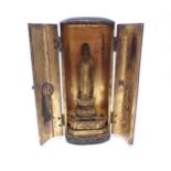 A portable Shrine having laquered finish, two doors open to reveal gilded wooden Buddha on lotus