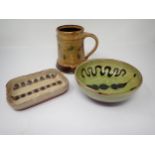 A Winchcombe Pottery Mug with stylised brand designs on a green/brown ground, having Michael