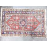 A North West Persian small Rug with central arrowhead and latch hook medallion on a red ground,