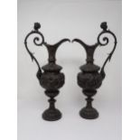 A pair of bronze pedestal Ewers in the classical style, with cherub heads to the scroll handles