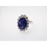 A Sapphire and Diamond Cluster Ring claw-set oval-cut sapphire, 4.02cts, within a frame of