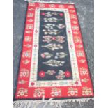 A bordered Kelim with floral design on a black central field, red ground border, 6ft x 3ft 1in