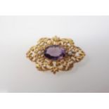 An Amethyst and Seed Pearl Brooch set oval-cut amethyst between two seed pearls within intricate